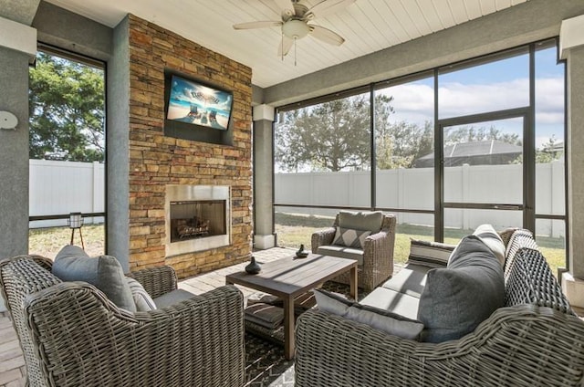 sunroom / solarium featuring ceiling fan, a wealth of natural light, and an outdoor stone fireplace