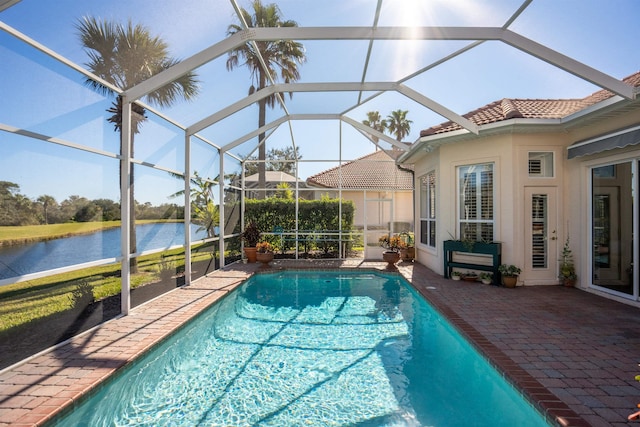 outdoor pool with a patio area, glass enclosure, and a water view