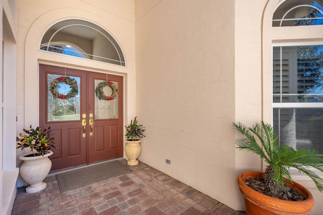 view of exterior entry featuring french doors and stucco siding