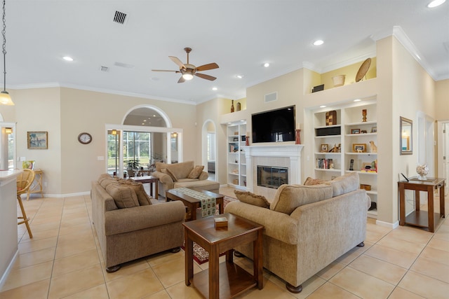 living area featuring built in features, crown molding, a fireplace, visible vents, and light tile patterned flooring