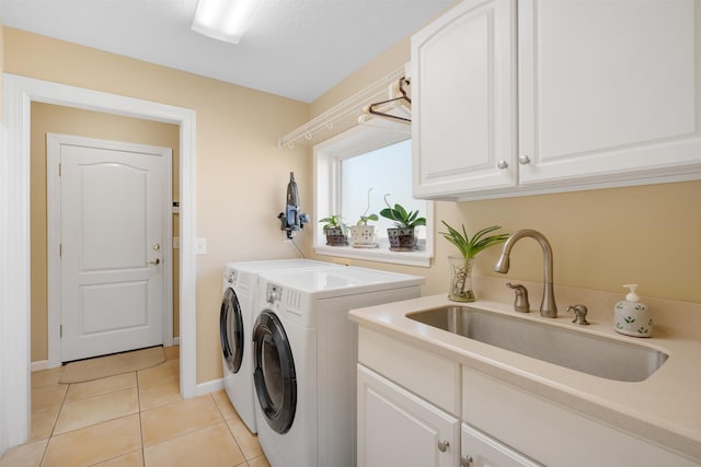 laundry room featuring washing machine and clothes dryer, light tile patterned floors, cabinet space, a sink, and a textured ceiling