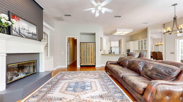 12232 Lashbrook Ct, Jacksonville, FL 32223 - living room featuring a chandelier, ceiling fan, wood finished floors, a tile fireplace, and built in shelves