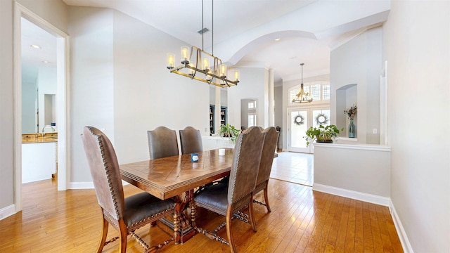 12232 Lashbrook Ct, Jacksonville, FL 32223 - dining area with a chandelier, light wood-style floors, baseboards, and arched walkways