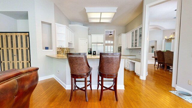12232 Lashbrook Ct, Jacksonville, FL 32223 - kitchen with stainless steel refrigerator with ice dispenser, open shelves, a peninsula, light wood-type flooring, and white cabinets
