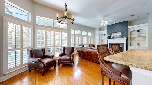 12232 Lashbrook Ct, Jacksonville, FL 32223 - living room featuring light wood-style flooring, a fireplace, a ceiling fan, and a chandelier