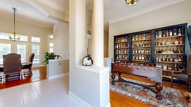 12232 Lashbrook Ct, Jacksonville, FL 32223 - bar featuring decorative columns, ornamental molding, baseboards, a chandelier, and tile patterned flooring