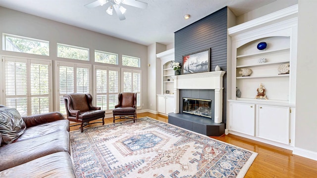 12232 Lashbrook Ct, Jacksonville, FL 32223 - living area featuring built in features, ceiling fan, a fireplace, baseboards, and light wood-style floors