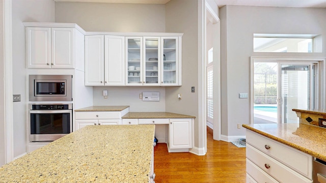 12232 Lashbrook Ct, Jacksonville, FL 32223 - kitchen featuring stainless steel appliances, light wood-style flooring, white cabinets, light stone countertops, and glass insert cabinets