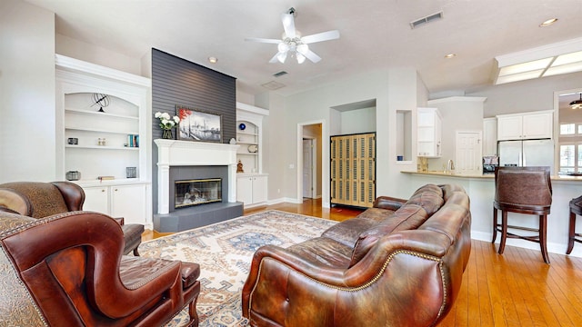 12232 Lashbrook Ct, Jacksonville, FL 32223 - living area with a ceiling fan, light wood-style floors, baseboards, built in shelves, and a tiled fireplace