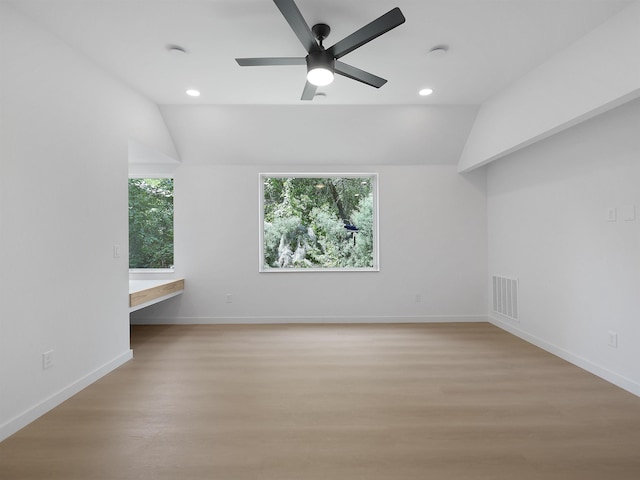 interior space with light wood-style floors, a ceiling fan, visible vents, lofted ceiling, and baseboards