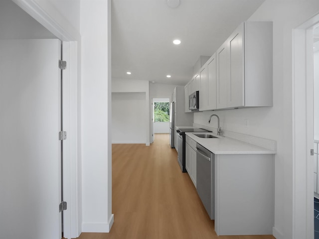 kitchen featuring a sink, light countertops, appliances with stainless steel finishes, recessed lighting, and light wood finished floors