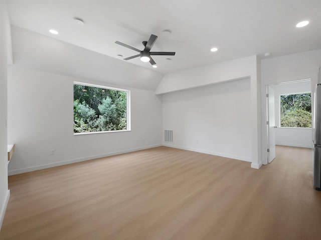 empty room featuring baseboards, a ceiling fan, light wood-style floors, and a healthy amount of sunlight