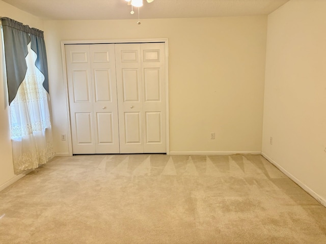 unfurnished bedroom featuring light colored carpet and a closet