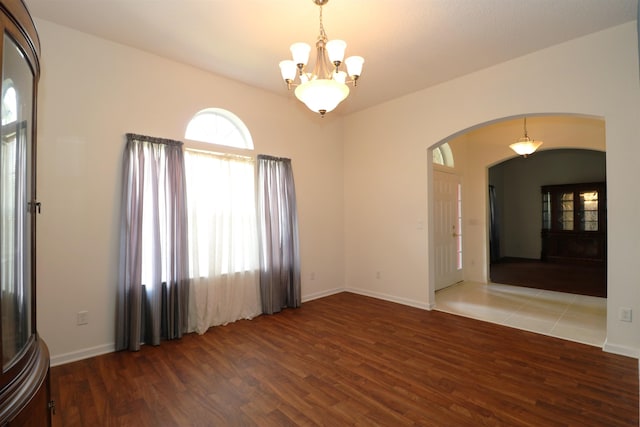 unfurnished room with hardwood / wood-style floors and an inviting chandelier