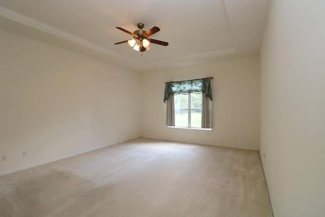 carpeted spare room featuring a tray ceiling and ceiling fan