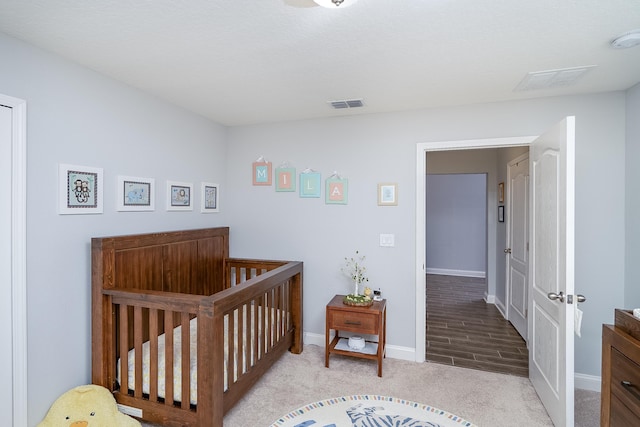 bedroom featuring light hardwood / wood-style flooring and a nursery area