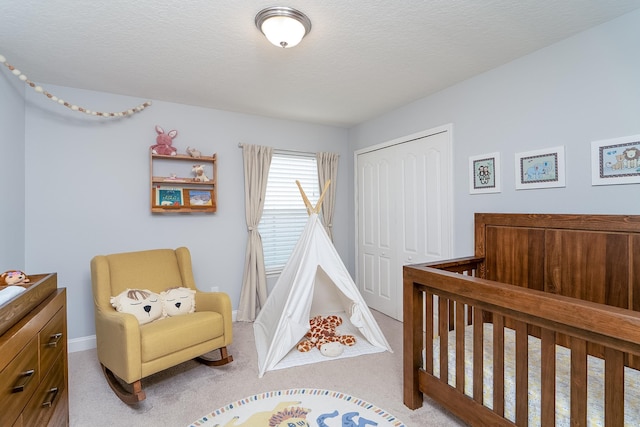 carpeted bedroom featuring a crib, a textured ceiling, and a closet