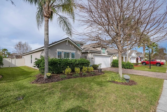 view of front of property with an attached garage, fence, decorative driveway, stucco siding, and a front lawn