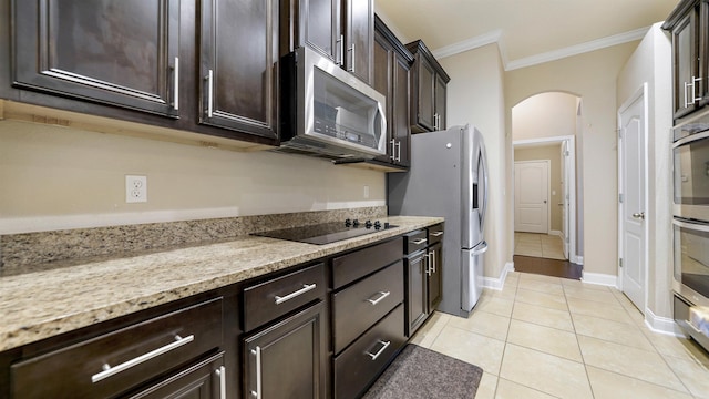 kitchen featuring light tile patterned flooring, stainless steel appliances, crown molding, light stone countertops, and dark brown cabinets