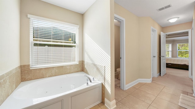 bathroom with a washtub, tile patterned floors, and toilet