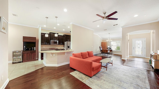 living room with wine cooler, hardwood / wood-style floors, ceiling fan with notable chandelier, and ornamental molding