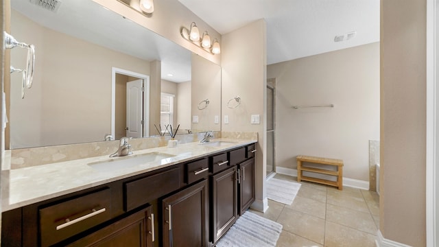 bathroom with a shower with door, vanity, and tile patterned floors