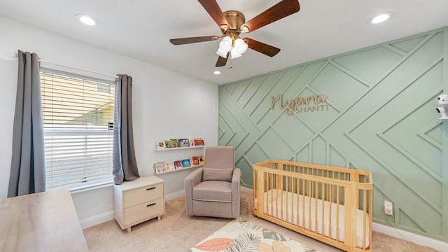 carpeted bedroom featuring a crib and ceiling fan