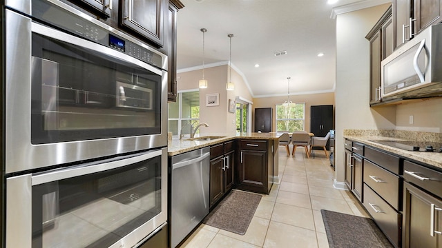 kitchen featuring vaulted ceiling, appliances with stainless steel finishes, pendant lighting, and dark brown cabinetry