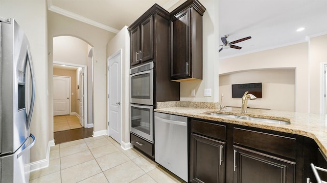 kitchen with appliances with stainless steel finishes, sink, ornamental molding, light tile patterned floors, and dark brown cabinets