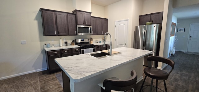 kitchen with a kitchen island with sink, a breakfast bar, sink, and appliances with stainless steel finishes