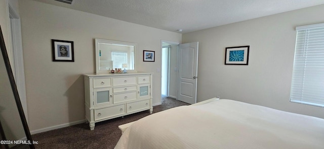 bedroom featuring dark carpet and a textured ceiling