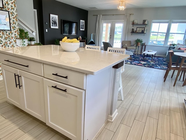 268 Sierras Loop, Saint Augustine, FL 32086 - kitchen with open floor plan, white cabinets, wood tiled floors, a kitchen island, and light stone countertops