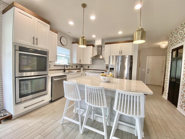268 Sierras Loop, Saint Augustine, FL 32086 - kitchen featuring appliances with stainless steel finishes, wood tiled floors, wall chimney range hood, backsplash, and white cabinets