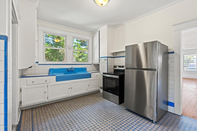 121 Washington St, Saint Augustine, FL 32084 - kitchen with a sink, appliances with stainless steel finishes, white cabinetry, crown molding, and tasteful backsplash