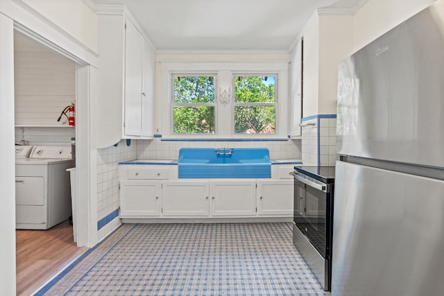 121 Washington St, Saint Augustine, FL 32084 - kitchen featuring washer and clothes dryer, white cabinets, stainless steel appliances, and a sink
