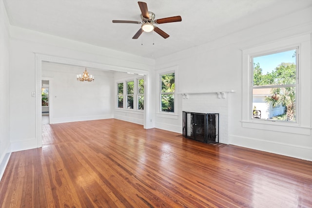 121 Washington St, Saint Augustine, FL 32084 - unfurnished living room with ceiling fan with notable chandelier, a brick fireplace, baseboards, and wood finished floors