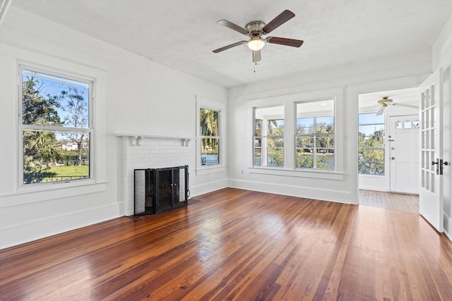 121 Washington St, Saint Augustine, FL 32084 - unfurnished living room featuring hardwood / wood-style floors, baseboards, a brick fireplace, and ceiling fan