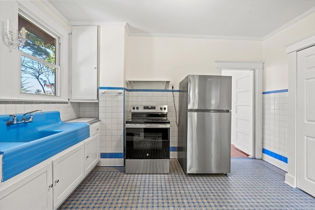 121 Washington St, Saint Augustine, FL 32084 - kitchen featuring tile walls, white cabinets, ornamental molding, and stainless steel appliances