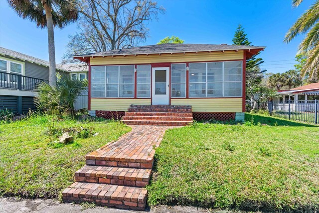121 Washington St, Saint Augustine, FL 32084 - bungalow-style home featuring entry steps, a front yard, fence, and a sunroom