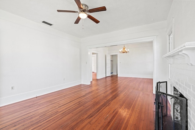 121 Washington St, Saint Augustine, FL 32084 - unfurnished living room featuring visible vents, ceiling fan with notable chandelier, wood finished floors, baseboards, and a brick fireplace