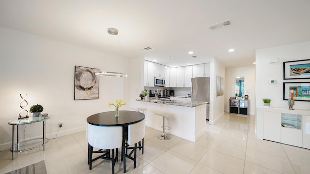 890 A1A Beach Blvd Unit 59, Saint Augustine, FL 32080 - kitchen featuring stainless steel appliances, a peninsula, light tile patterned flooring, white cabinets, and recessed lighting