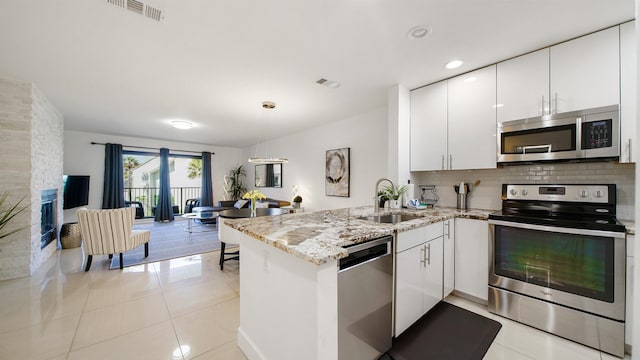 890 A1A Beach Blvd Unit 59, Saint Augustine, FL 32080 - kitchen featuring appliances with stainless steel finishes, a peninsula, white cabinetry, light tile patterned flooring, and light stone counters