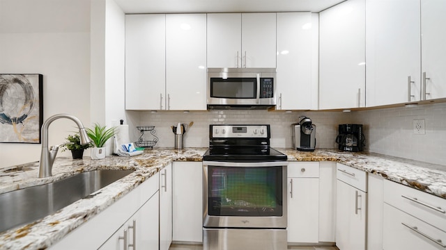 890 A1A Beach Blvd Unit 59, Saint Augustine, FL 32080 - kitchen with appliances with stainless steel finishes, white cabinetry, tasteful backsplash, and light stone counters