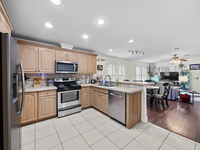 kitchen featuring decorative backsplash, stainless steel appliances, ceiling fan, sink, and light tile patterned floors