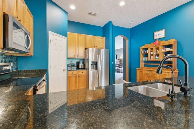 241 N Hidden Tree Dr, Saint Augustine, FL 32086 - kitchen featuring appliances with stainless steel finishes, arched walkways, decorative backsplash, dark stone countertops, and a textured ceiling