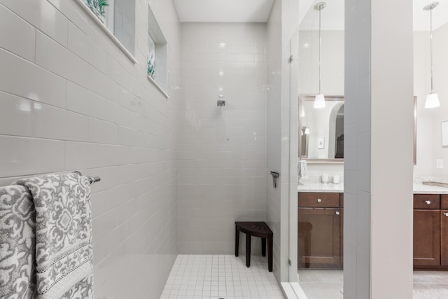 bathroom with tile patterned flooring, vanity, and tiled shower