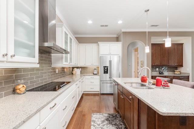 kitchen featuring pendant lighting, sink, appliances with stainless steel finishes, an island with sink, and wall chimney exhaust hood