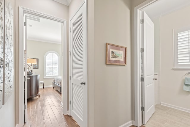 corridor featuring ornamental molding and light hardwood / wood-style floors