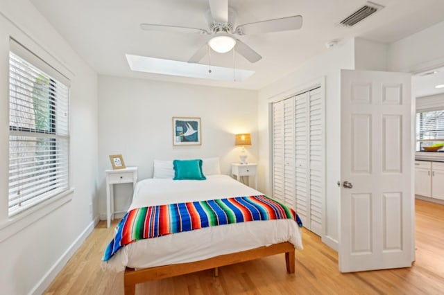 bedroom featuring ceiling fan, light wood-type flooring, and a skylight