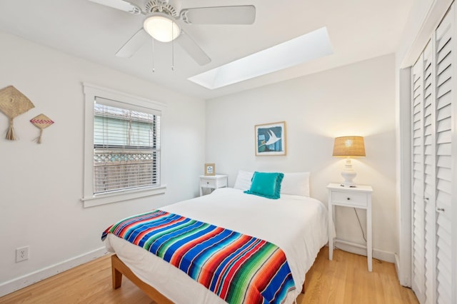 bedroom featuring ceiling fan, a skylight, and light hardwood / wood-style flooring